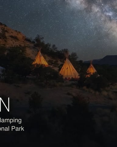 Illuminated glamping tents and yurt under starry night sky with Milky Way visible above desert landscape and red rock formations
